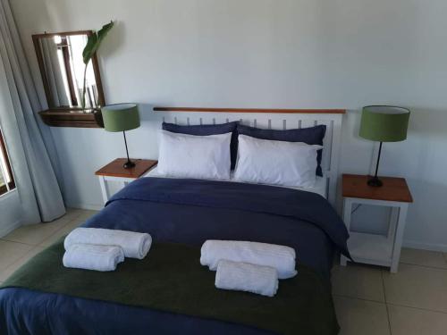 a bedroom with a blue bed with two towels on it at Fair Haven Guest Suite Self-catering in Marina Beach