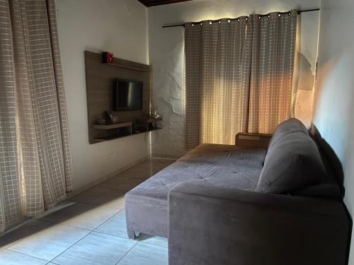 a bedroom with a bed and a couch and a tv at Casa de Andirá in Andirá