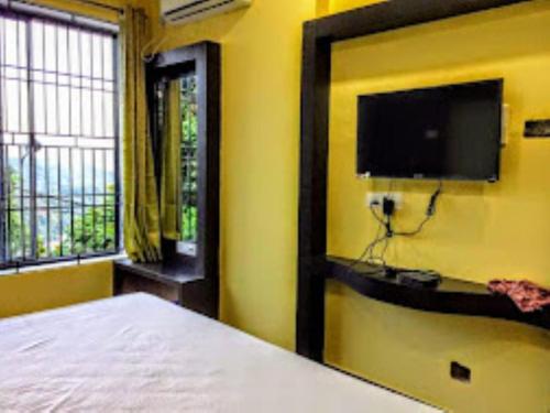 - une chambre avec un lit et une télévision à écran plat dans l'établissement Bhargav Residency , Guwahati, à Guwahati