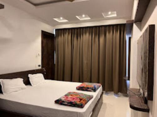 - une chambre avec un lit et une fenêtre avec des rideaux dans l'établissement Bhargav Residency , Guwahati, à Guwahati