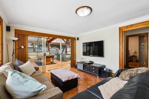 a living room with a couch and a tv at Spacious home near Glenelg in South Plympton