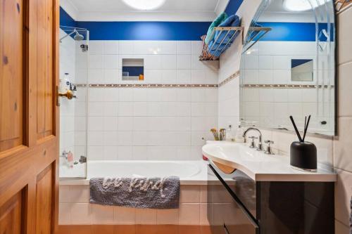 a bathroom with a white tub and a sink at Spacious home near Glenelg in South Plympton