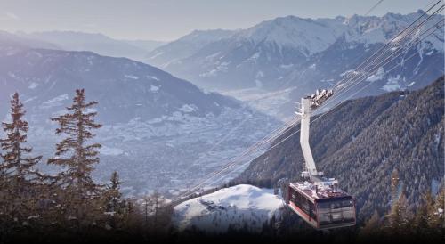 a gondola flying over a snow covered mountain at Relax Suite in Merano