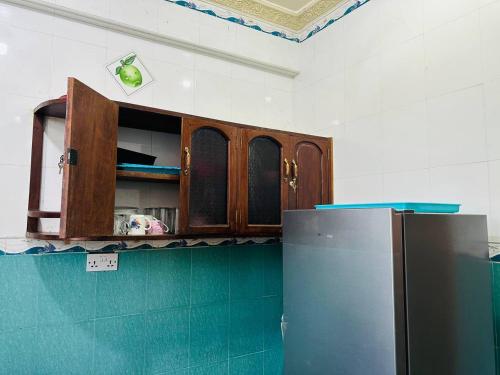 a kitchen with wooden cabinets and a refrigerator at Pazuri apartment in Ngambo