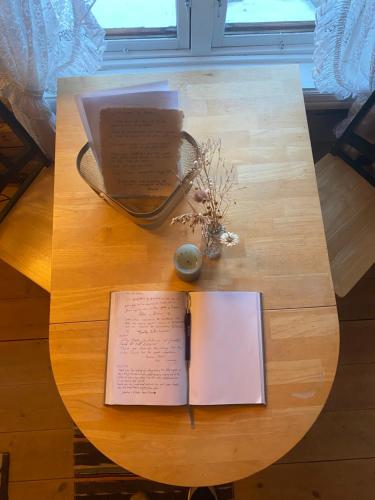 a table with a book and a pen and a notebook at Stallen - koselig lite hus på gårdstun in Skjåk