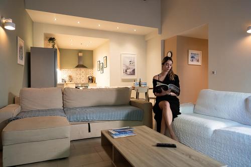 a woman sitting on a couch in a living room at Linas Home - Kalamata Mediterranean Villas in Kalamata