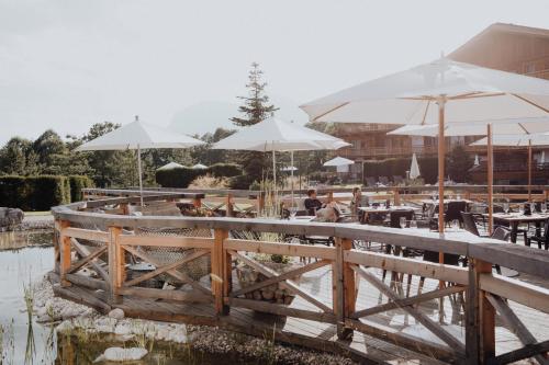 a restaurant with tables and umbrellas next to a pond at Kaiserlodge in Scheffau am Wilden Kaiser