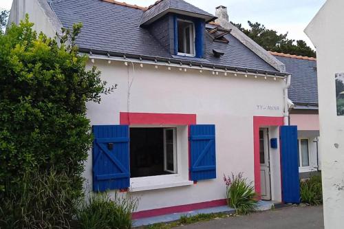 ein weißes und blaues Haus mit blauen Fensterläden in der Unterkunft ty anna in Le Palais
