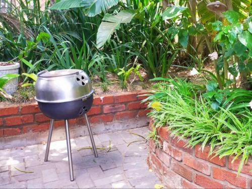 a grill sitting on a brick wall in a garden at Pompano Place Rest in Richards Bay