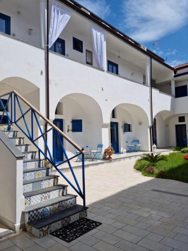 eine Treppe, die zu einem weißen Gebäude mit blauen Türen führt in der Unterkunft Suite FURORE in Aversa