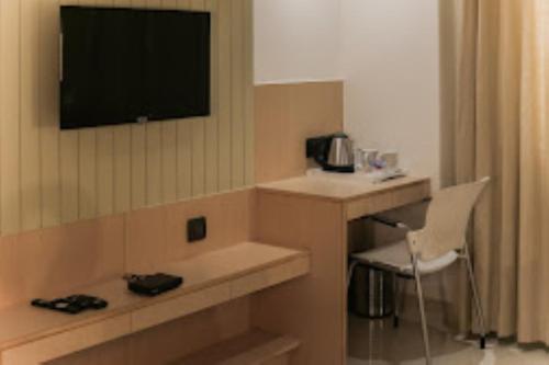 Habitación de hotel con escritorio y TV en la pared en MAX PRIME, Madurai, en Madurai