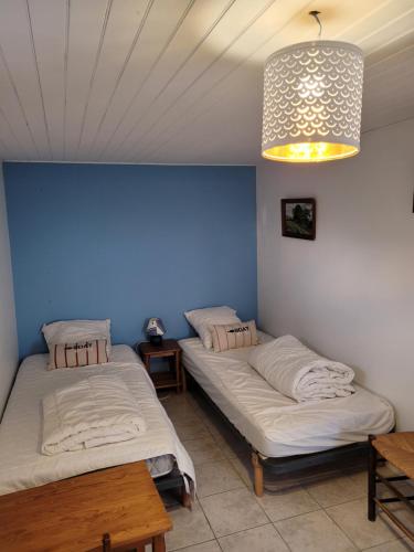 twee bedden in een kamer met een blauwe muur bij Ker Lucie- Les Gîtes de la Côte d'Amour ! in Batz-sur-Mer