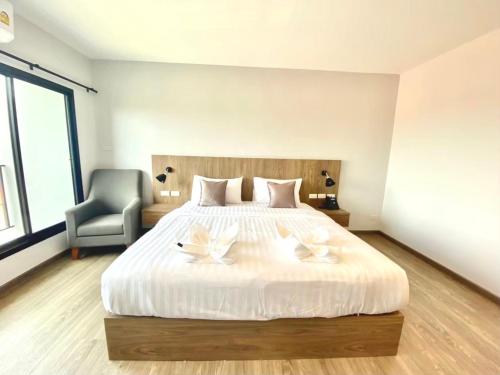 a bedroom with a large white bed with a chair at Nakara Hotel, Ubon Ratchathani in Ban Na Kham