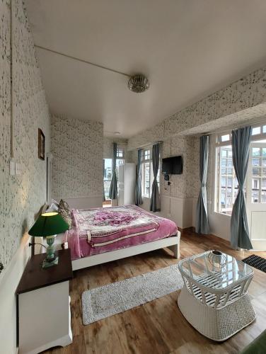 a bedroom with a pink bed and a table at Silversky Guesthouse - Shillong in Shillong