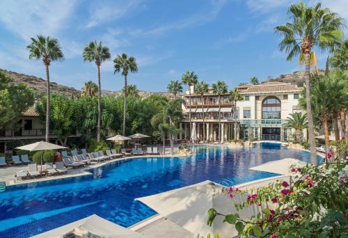 a large swimming pool with palm trees and a building at Columbia Beach Resort in Pissouri