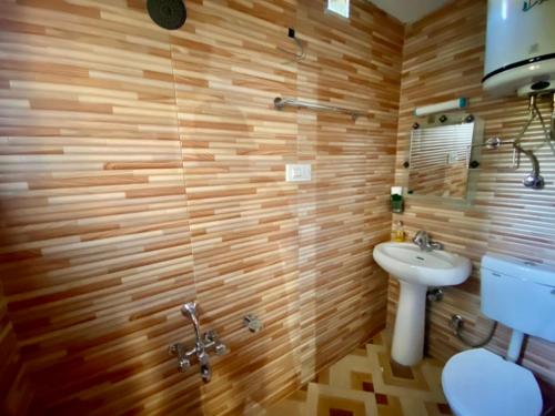 La salle de bains est pourvue de murs en bois, de toilettes et d'un lavabo. dans l'établissement The Upscale Inn, à Srinagar