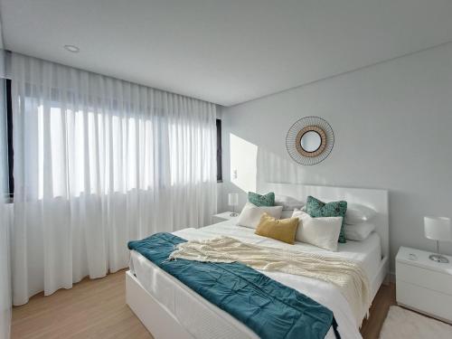 a white bedroom with a large bed and a mirror at Casa Urban Coastal - City Center in Ponta Delgada