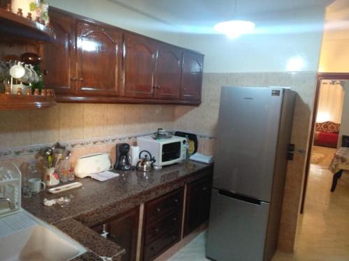 a kitchen with wooden cabinets and a refrigerator at Appartement Bio Hamria Meknes in Meknès