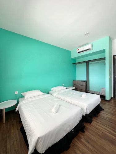 two beds in a room with a blue wall at Roxy Sematan Beach Townhouse Deluxe 7 ,8 ,9, 10 ,11 ,12 in Sematan