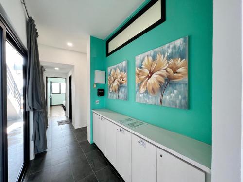 a hallway with a green wall with two paintings at Roxy Sematan Beach Townhouse Deluxe 7 ,8 ,9, 10 ,11 ,12 in Sematan