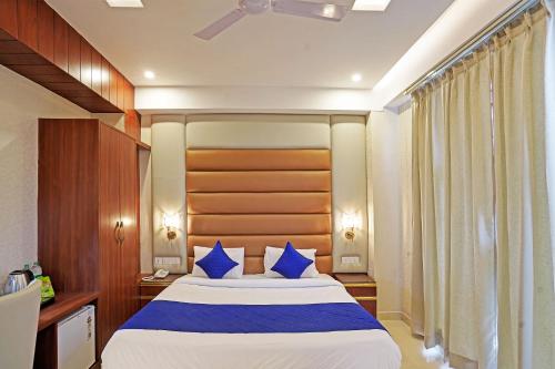 um quarto com uma cama grande e almofadas azuis em Diamond Admire Hotel & Banquets by MMD em Noida