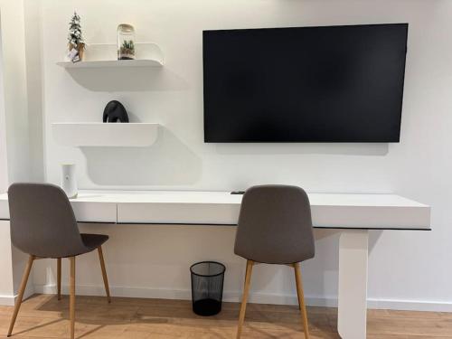 a white desk with two chairs and a television on a wall at Boutique Flat in the City Center in Tirana