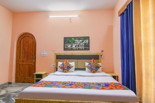 1 dormitorio con 1 cama con paredes de color naranja y cortinas azules en FabExpress Malti Guest House en Kulu