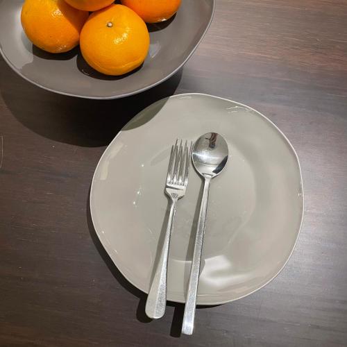 a white plate with a fork and a bowl of oranges at Nhà mình Homestay in Rach Gia