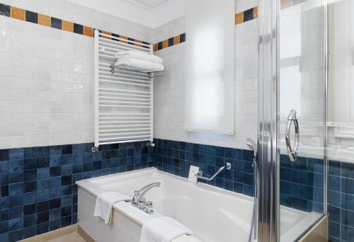a bathroom with a tub and a blue tiled wall at Columbia Beach Resort in Pissouri