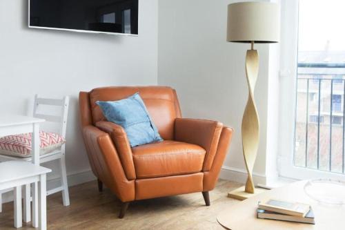 a brown chair with a blue pillow in a living room at Stunning Flat in Hull's Vibrant Fruit Market & Marina in Hull