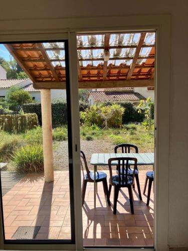 d'une terrasse avec une table, des chaises et une porte en verre. dans l'établissement Maison bord de mer, à Hyères