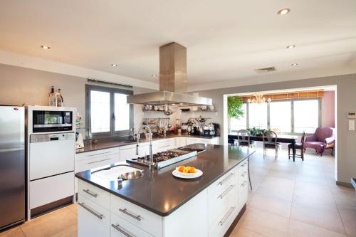 une cuisine avec des armoires blanches et un four à plaques de cuisson dans l'établissement Villa Fiorella, à Porto-Vecchio