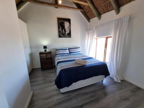 um quarto com uma cama com lençóis azuis e uma janela em 24 Arniston Village, Melkbosstrand em Melkbosstrand