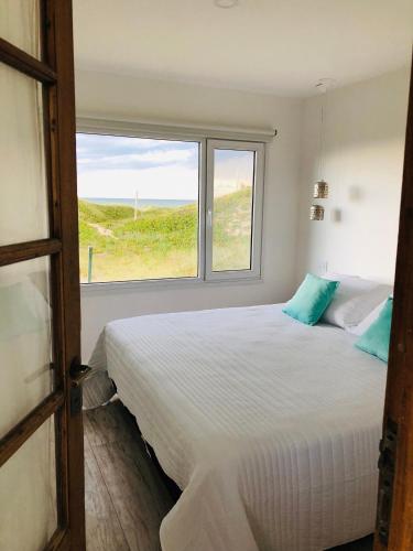 a bedroom with a large white bed and a window at La Casa de Caro Playa in Mar de Cobo