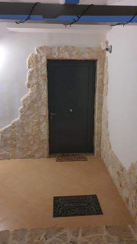 une porte noire dans un mur en pierre avec un tapis dans l'établissement MERCADANTE - Luxury Holiday House, à Cassano delle Murge