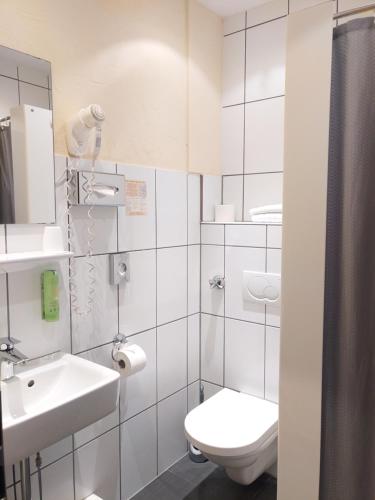 a white bathroom with a toilet and a sink at Hotel Auf der Bühn in Malsch