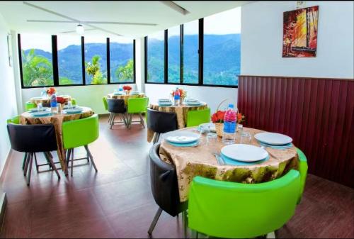 une salle à manger avec des tables et des chaises vertes dans l'établissement The View Munnar, à Anachal