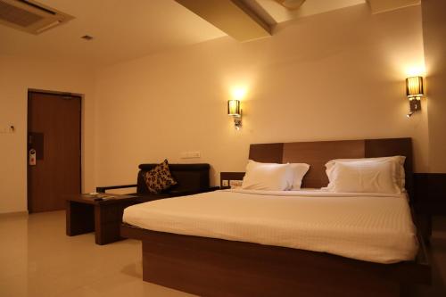 蒂魯普的住宿－Hotel Maniam Classic West Wing，卧室配有一张带白色床单和枕头的大床。