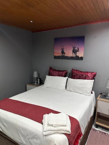 een slaapkamer met een groot wit bed met rode kussens bij KKK Guesthouse in Secunda