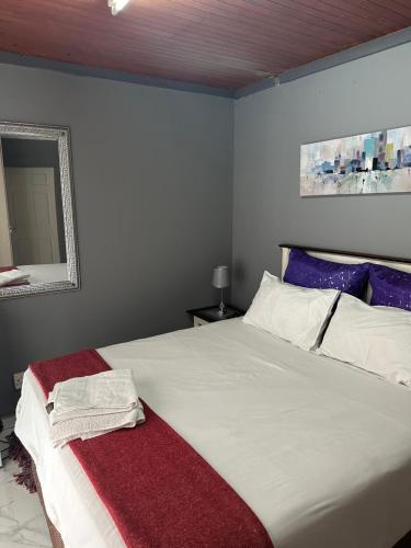 een slaapkamer met een groot wit bed en een spiegel bij KKK Guesthouse in Secunda