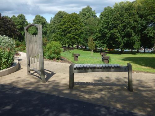 a wooden bench in a park with trees and grass at Urban 2 Bedroom with Parking in West Bromwich