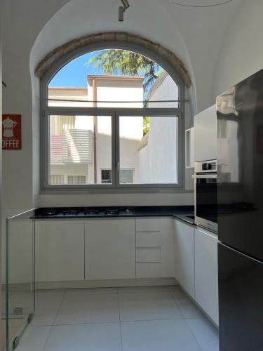 a kitchen with an arched window and white cabinets at Da Carlin in Cesena