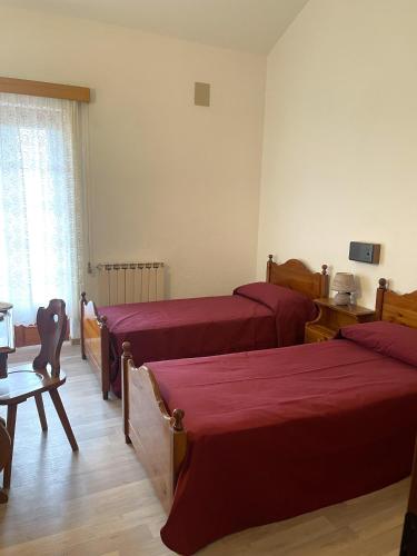 a bedroom with two beds and a table and a window at HOTEL DU SOLEIL in Torgnon