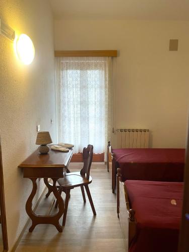 a living room with a table and a bed and a window at HOTEL DU SOLEIL in Torgnon