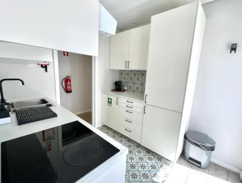 una pequeña cocina con armarios blancos y fregadero en Campus 121 en Faro