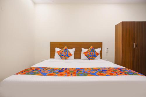 a bedroom with a large white bed with colorful sheets and pillows at FabHotel Air Live in Hyderabad