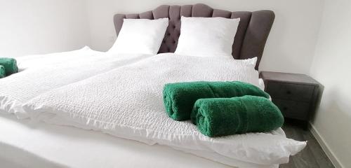a bed with green and white sheets and pillows at Pension Lahntal 