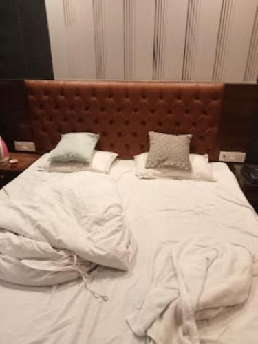 1 cama grande con sábanas y almohadas blancas en Hotel Rajdarbar Fatehpur, en Fatehpur Sīkri