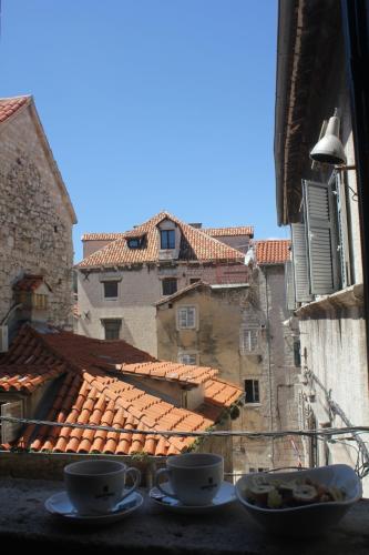 einen Blick auf eine Stadt aus einem Fenster mit zwei Tassen in der Unterkunft Slavija Culture Heritage Hotel in Split