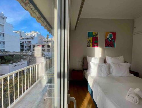 a bedroom with a bed and a balcony with a window at Spacious 2BDs Apt With Acropolis View In Center in Athens
